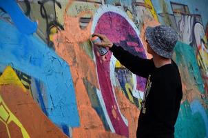 kharkov, ukraine - 27 mai 2022 festival des arts de la rue. les jeunes gars dessinent des graffitis sur de vieux murs en béton au centre de la ville. le processus de peinture sur les murs avec des bombes aérosols photo