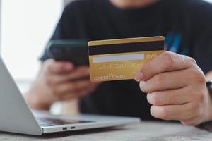 achats en ligne e-commerce ou concept de services bancaires par Internet.main d'homme tenant une carte de crédit et utilisant un ordinateur portable.paiement et comptabilité de la finance d'entreprise. photo