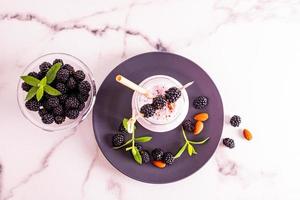 vue de dessus d'une bouteille de smoothies fraîchement préparés ou d'un cocktail aux noix et aux mûres. fond blanc en marbre. délicieux dessert, collation. photo