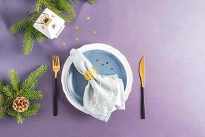 mettre la table de fête pour le nouvel an et noël. assiettes et couverts, serviette en tissu avec décoration. vue de dessus. nappe grise. photo