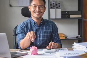 homme tenant une pièce de monnaie pour déposer une tirelire pour économiser de l'argent pour l'avenir de la famille, économiser des idées. photo