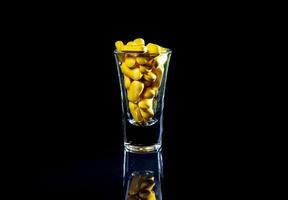 pilules oranges blanches dans un verre à vin. en pot. dans un seau isolé sur un ensemble noir de capsules et de pilules à l'intérieur de gros plan, photo