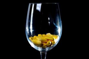 pilules oranges blanches dans un verre à vin. en pot. dans un seau isolé sur un ensemble noir de capsules et de pilules à l'intérieur de gros plan, photo