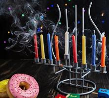 fond de hanukkah fête juive. un plat traditionnel est les beignets sucrés. table de hanukkah chandelier avec bougies et toupies sur fond noir. allumer des bougies de 'Hanoucca. copie espace photo