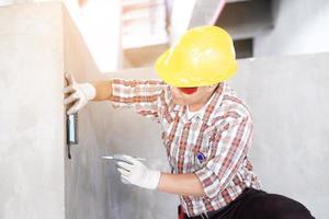 travailleur dans la mesure du mur avec niveleur laser sur le chantier, ingénieurs au travail vérifiant le projet de construction avec une machine de niveau laser pendant les travaux de mesure sur site photo