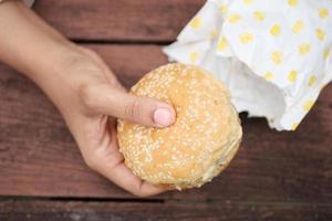 main de femme tenant un burger de boeuf vue de dessus photo