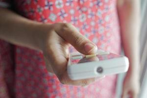 gros plan sur une main de femme tenant la télécommande de la climatisation. photo