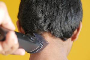 couper les cheveux avec une tondeuse à cheveux sur fond jaune photo