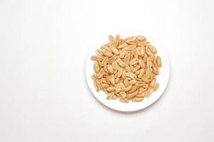 cacahuètes naturelles sur une assiette sur fond blanc photo