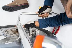 les gens réparent une moto utilisent une clé et un tournevis pour travailler photo