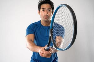 un joueur de tennis masculin tenant une raquette de tennis avec une expression déterminée et des yeux sur fond blanc. photo