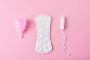 serviette hygiénique, coupe menstruelle et tampon sur fond rose photo