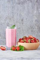 smoothie aux fraises dans un bocal en verre et fraises fraîches dans un bol en bois photo