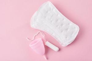 serviette hygiénique, coupe menstruelle et tampon sur fond rose photo