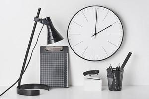 fournitures de bureau, lampe et horloge murale sur blanc photo