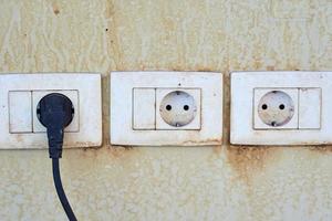Trois anciennes prises damger sur un mur avec cordon câble branché dans une prise photo