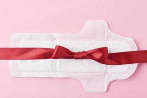 serviette hygiénique et ruban rouge sur fond rose photo