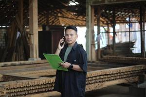 jeune homme asiatique patron d'une entreprise de bois appelant son amie et vérifiant la qualité photo