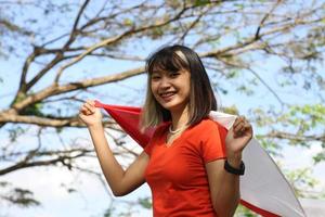 belle jeune femme asiatique portant le drapeau indonésien avec un visage joyeux photo