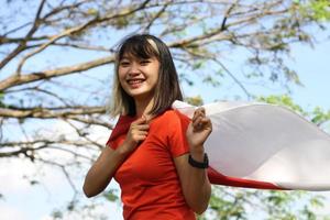 belle jeune femme asiatique portant le drapeau indonésien avec un visage joyeux photo