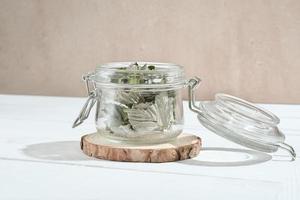 bocal en verre transparent avec feuilles de framboise sèches pour tisane. herbes pour calmer le thé. ingrédients pour la médecine alternative, garde-manger photo