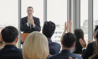 haut-parleur masculin applaudissant avec le public lors d'un séminaire d'entreprise dans la salle de conférence. photo
