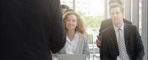 public d'affaires de diversité heureux d'écouter un homme exécutif parlant lors d'un séminaire d'entreprise. concept de bannière, vue arrière, effet de lumière. photo