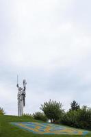 statue de la patrie contre le ciel bleu. armoiries de l'ukraine sur la pelouse, bordées de pierres bleues et jaunes. le trident, symbole officiel de l'État. Ukraine, Kyiv - 08 octobre 2022. photo