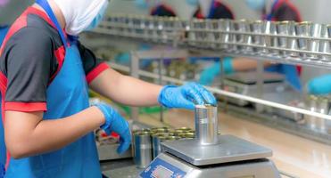 travailleur travaillant dans une usine de conserves alimentaires. industrie alimentaire. usine de conserves de poisson. ouvriers pesant des sardines en conserve sur une balance. travailleur dans la chaîne de production de transformation des aliments. l'industrie agroalimentaire. photo