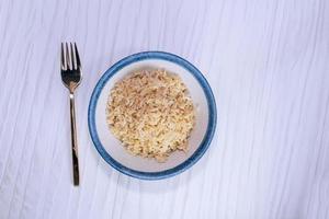 Riz brun dans un bol ont une fourchette isolé sur fond blanc photo