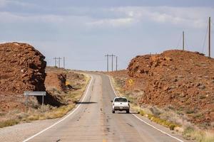 voiture se déplaçant sur une route de campagne au milieu de formations rocheuses pendant une journée ensoleillée photo