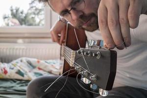 accordage de la guitare acoustique. un homme concentré répare un instrument de musique à cordes, à l'intérieur. photo