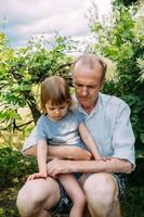 une petite fille embrasse son grand-père lors d'une promenade en été à l'extérieur. photo