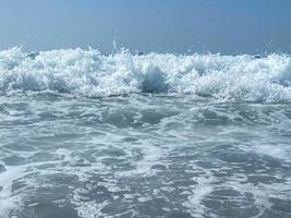 belle mer avec des vagues éclaboussant de l'eau bleue claire et scintillante chaude dans une station balnéaire du sud de la campagne orientale tropicale chaude. arrière-plan, texture photo