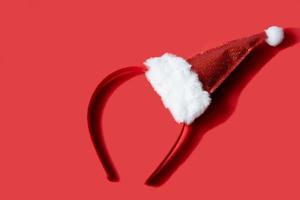 bonnet de noel rouge du nouvel an, bandeau, sur fond rouge. photographie minimaliste et élégante sur le thème de noël photo