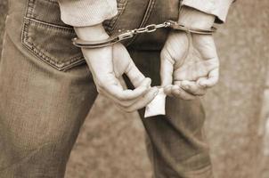 trafiquant de drogue arrêté dans les menottes de la police avec un petit paquet de drogue d'héroïne sur fond de mur sombre photo