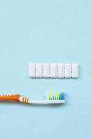 la brosse à dents et les chewing-gums se trouvent sur un fond bleu pastel. vue de dessus, mise à plat. notion minimale photo