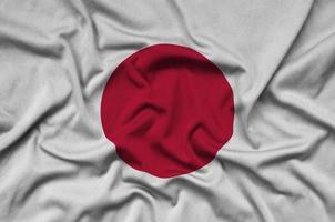 le drapeau du japon est représenté sur un tissu de sport avec de nombreux plis. bannière de l'équipe sportive photo