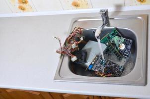 matériel dans l'évier de la cuisine sous le concept métaphorique de nettoyage de l'ordinateur de débit d'eau photo