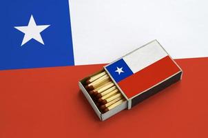 le drapeau du chili est affiché dans une boîte d'allumettes ouverte, qui est remplie d'allumettes et repose sur un grand drapeau photo