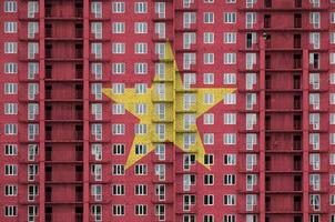 drapeau du vietnam représenté dans des couleurs de peinture sur un immeuble résidentiel à plusieurs étages en construction. bannière texturée sur fond de mur de brique photo