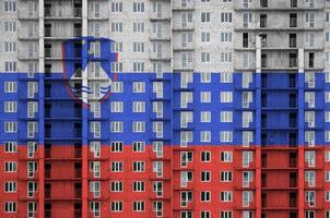 drapeau de la slovénie représenté dans des couleurs de peinture sur un immeuble résidentiel à plusieurs étages en construction. bannière texturée sur fond de mur de brique photo