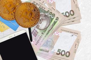 500 billets de hryvnias ukrainiens et bitcoins dorés avec smartphone et cartes de crédit. concept d'investissement en crypto-monnaie. minage ou commerce de crypto photo