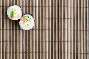 les rouleaux de sushi reposent sur un tapis de couture en paille de bambou. cuisine asiatique traditionnelle. vue de dessus. minimalisme à plat tourné avec espace de copie photo