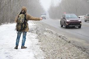 un homme avec un grand sac à dos montrant les pouces vers le haut pour l'auto-stop du photo