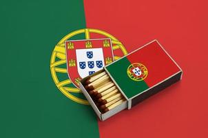 le drapeau du portugal est affiché dans une boîte d'allumettes ouverte, qui est remplie d'allumettes et repose sur un grand drapeau photo