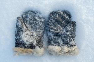 mitaines rétro recouvertes de neige, daim avec fourrure naturelle sur la neige, par une journée d'hiver glaciale. vue de dessus. photo