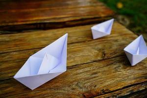 origami, bateau en papier blanc isolé sur un plancher en bois. les bateaux en papier signifient marcher. sentiment de liberté leadership photo