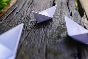 origami, bateau en papier blanc isolé sur un plancher en bois. les bateaux en papier signifient marcher. sentiment de liberté leadership photo