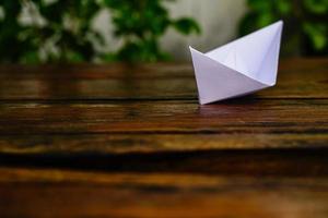 origami, bateau en papier blanc isolé sur un plancher en bois. les bateaux en papier signifient marcher. sentiment de liberté leadership photo